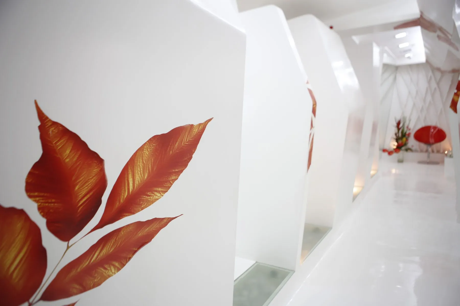 Frosted white corridor at Smiles By Dr. Cecile with the backlit hand-painted leaf panels leading to the treatment rooms